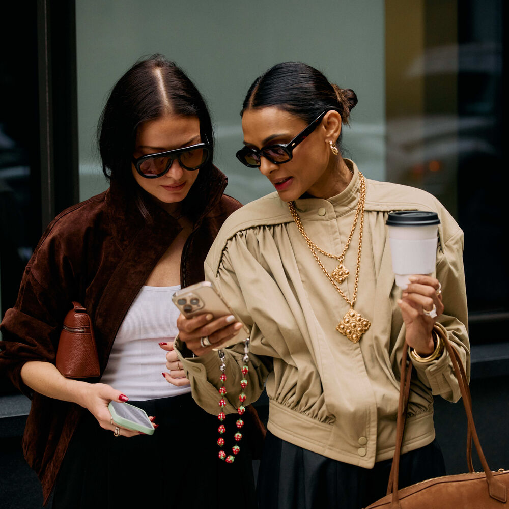 Two woman looking at their phones at fashion week