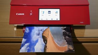 The Canon PIXMA TS8320, one of the best all-in-one printers, printing on a desk