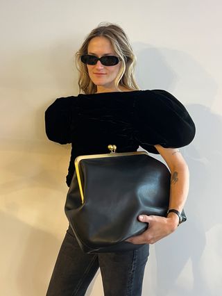  @elizagracehuber wearing a black top and jeans and a black Coach clasp bag.