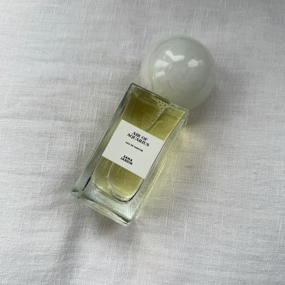 An image showing a bird's eye view of of the Sana Jardin Air of Aquarius perfume on a white linen background