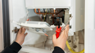 pair of hands opening a boiler with tools
