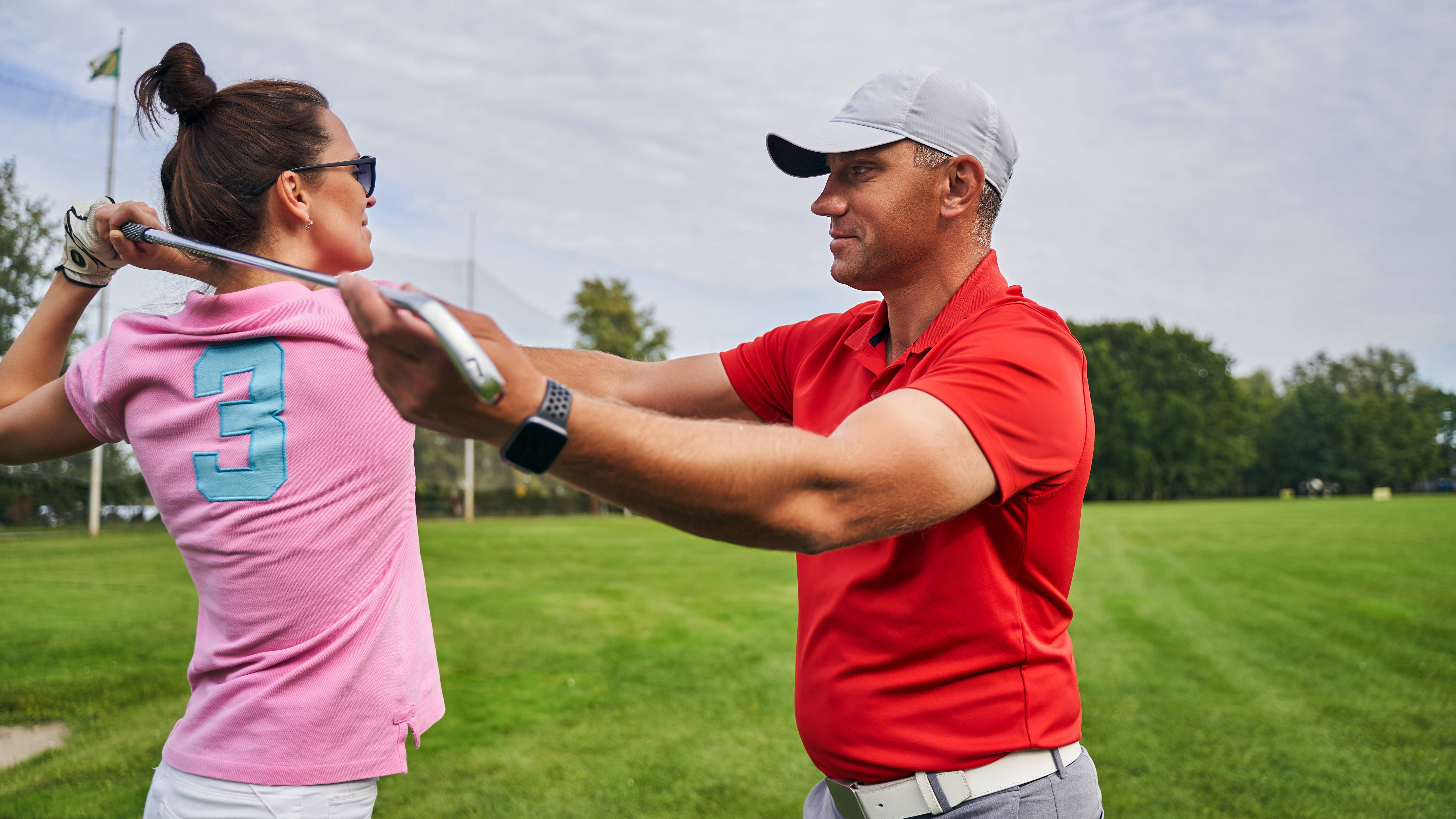 Golf coach instructing a female pupil