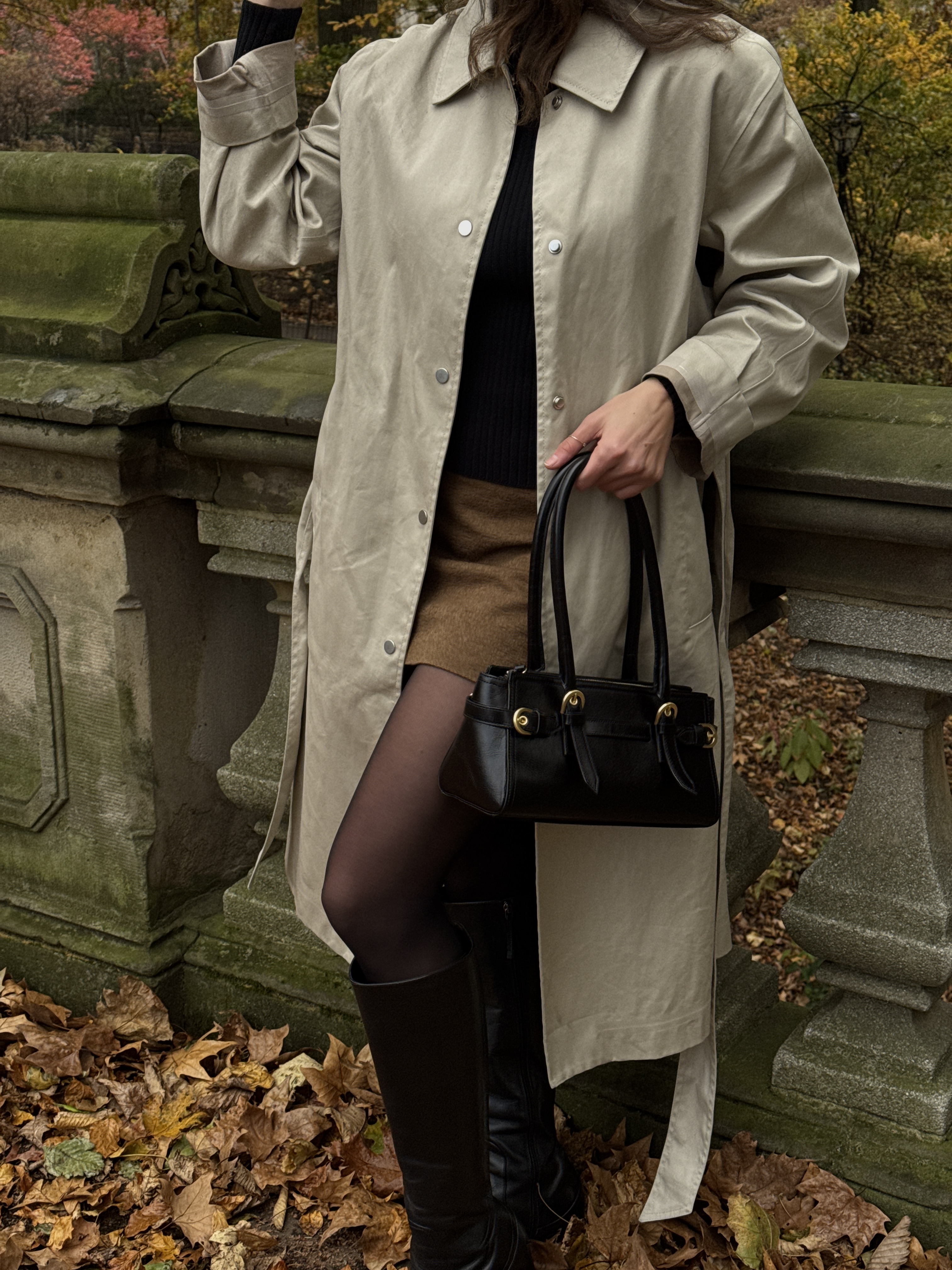 Kathryn Zahorak posing in trench coat, black handbag, brown skirt, and boots