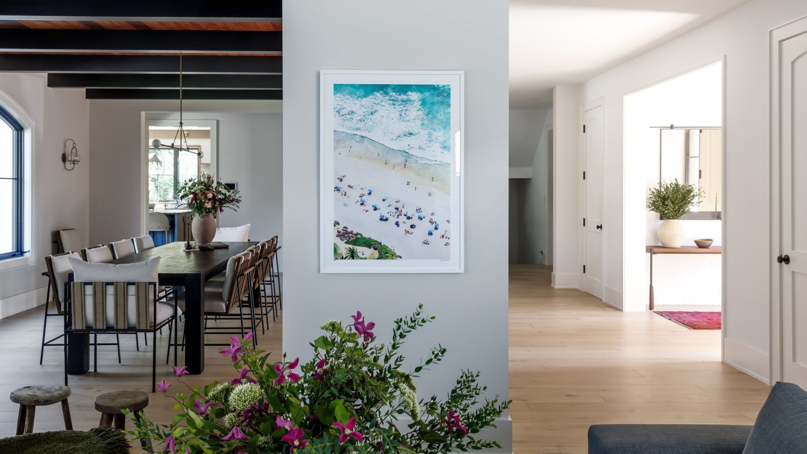 Open plan living space showing dining room on left, entryway on right with florals and artwork