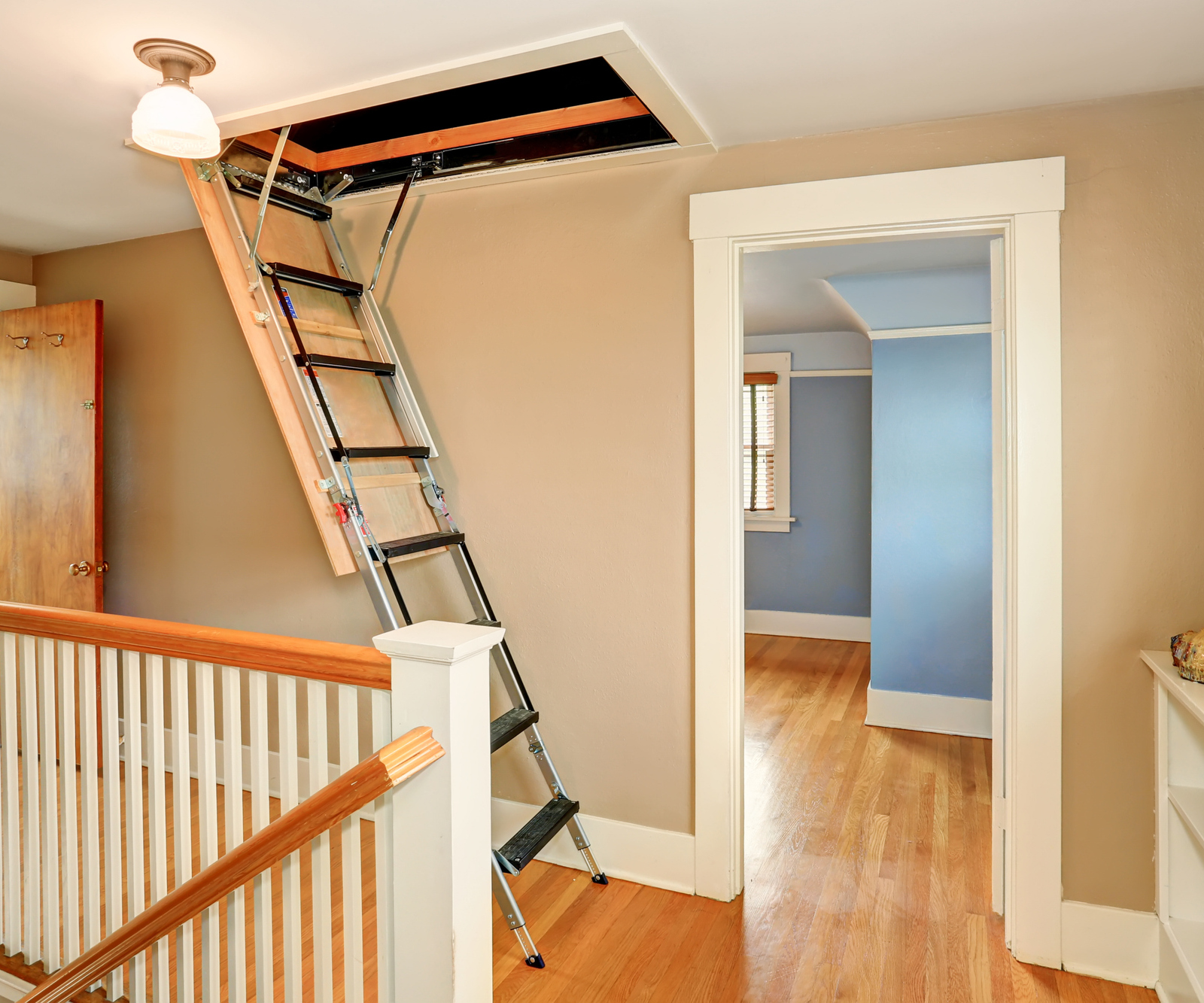 An extended loft ladder shown descending from a loft hatch within a home