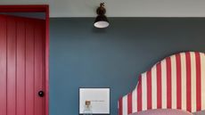 A bedroom with blue walls, and red and white striped headboard, and red door trim 