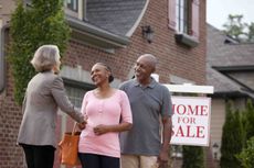 Older couple in front a for sale sign