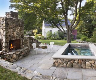 large plunge pool hot tub on a backyard patio with an outdoor fireplace