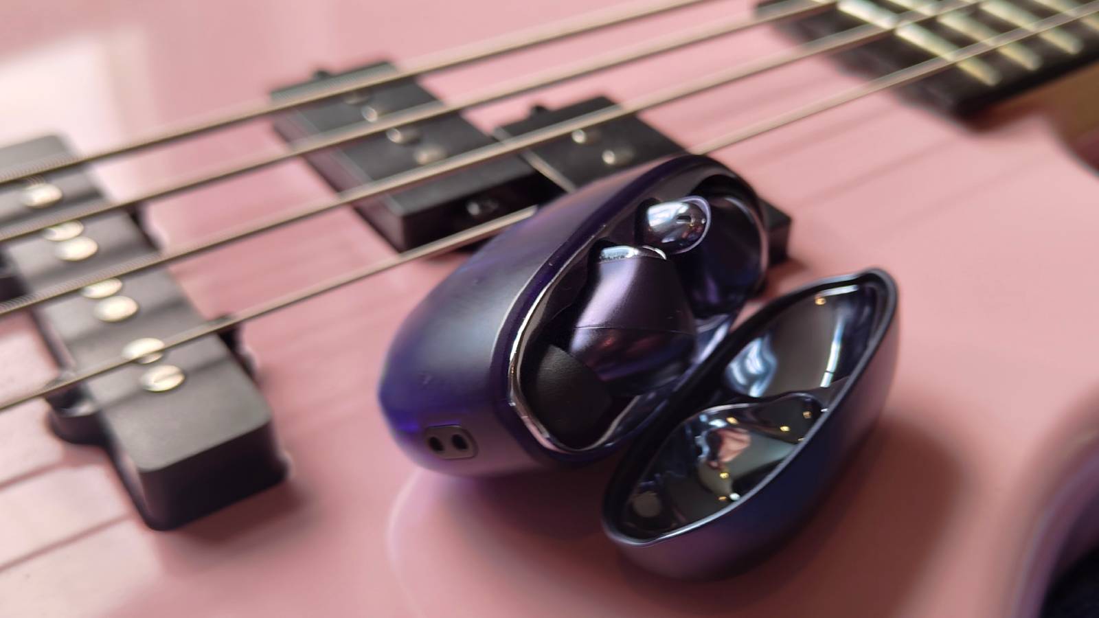The Creative Aurvana Ace 3 buds and case on a pink bass guitar.