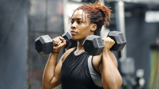 young woman working out with hand weights in a fitness gym
