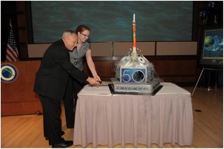 National Reconnaissance Office Director Bruce Carlson and cake design winner, Alli Taylor, cutting the official NRO birthday cake to mark the 50th anniversary of the U.S. space surveillance agency..