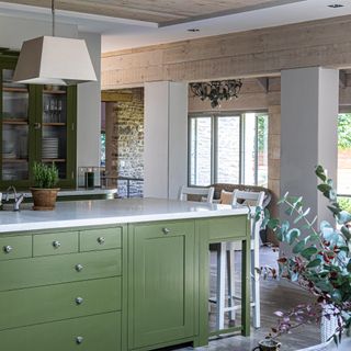 olive green kitchen with natural wood panelling in Cotswolds