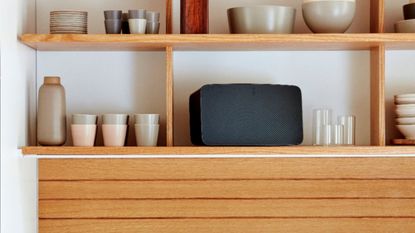 Sonos Five speaker within kitchen unit beside mugs, bowls and other kitchen tools