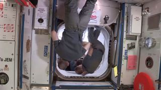 NASA astronaut Chris Cassidy (background) and Russian cosmonauts Anatoly Ivanishin and Ivan Vagner assist with closing the hatch to the Crew Dragon at the International Space Station, on Aug. 1, 2020.