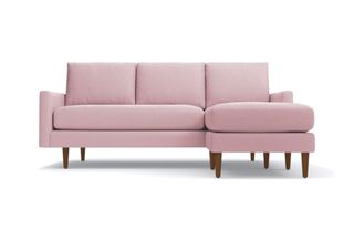 A pink velvet sectional sofa with pecan wood legs