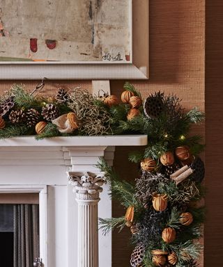 Christmas mantel decor with a garland with dred oranges, cinnamon and pine cones