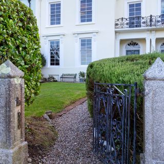 Gated entrance to grass lawn and gravel path in front garden