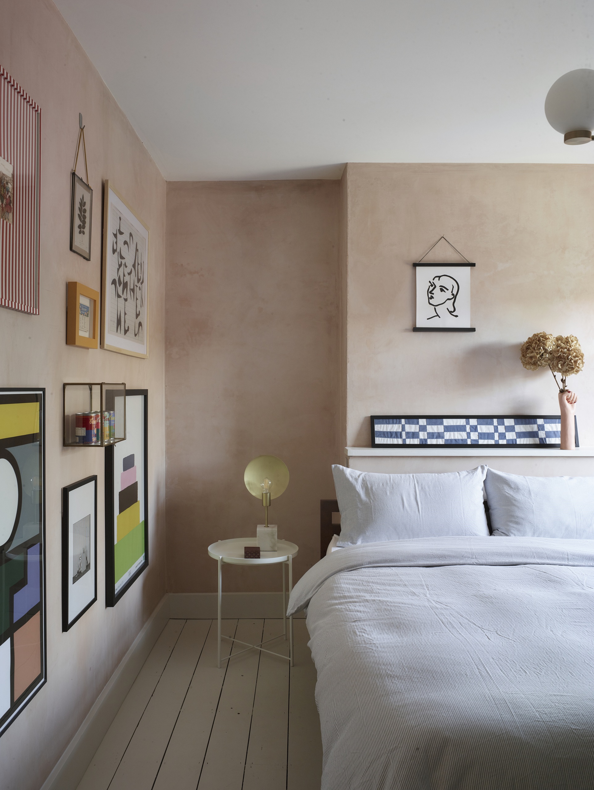 a bedroom with plaster walls, art, and a minimalist bed