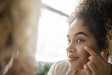 a woman assessing her dark circles in a mirror
