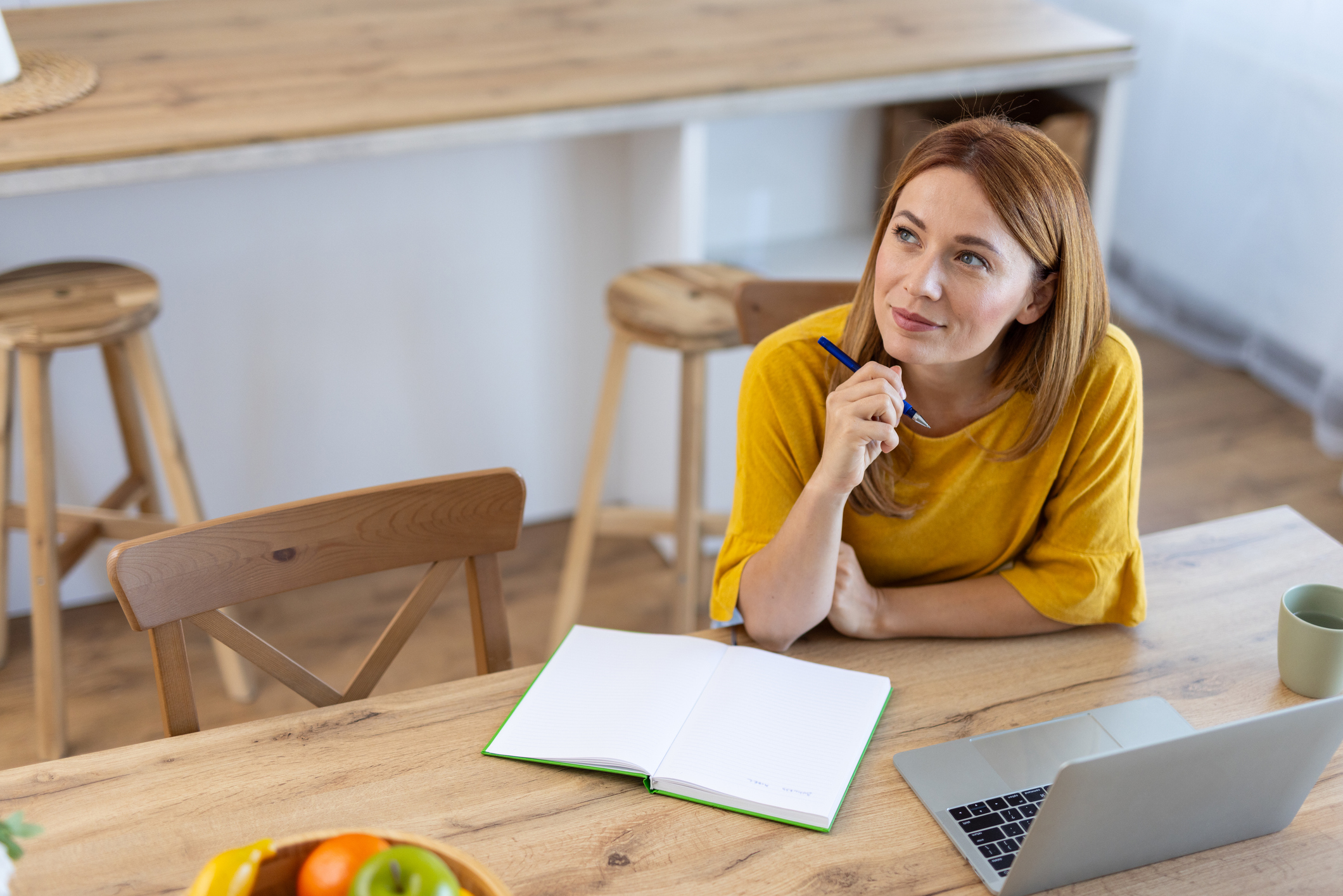 A thoughtful woman sits at a wooden table, reflecting on investment ideas for her self-invested personal pension (Sipp)