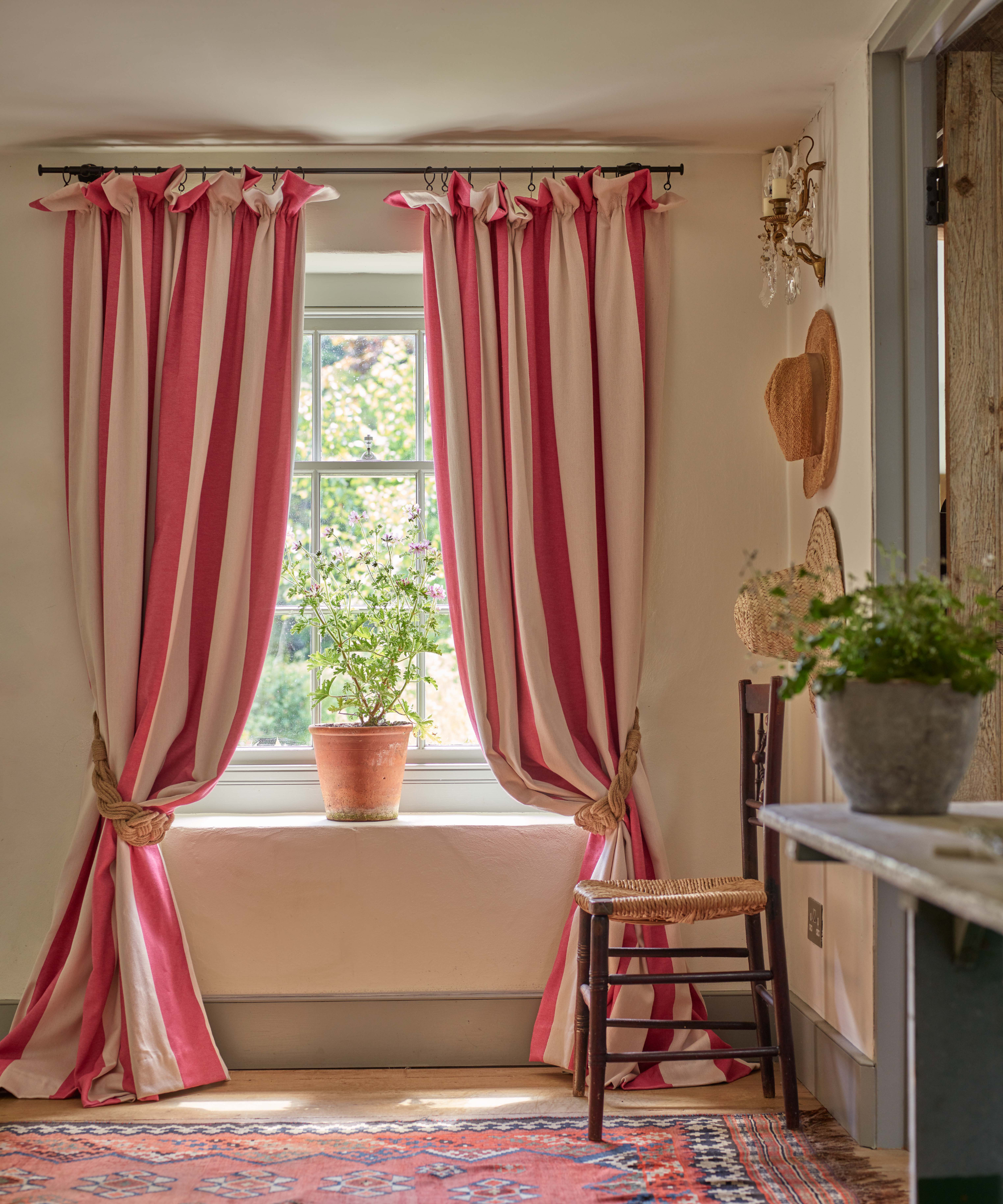 red and pink striped curtains in front of a window with a potted plant