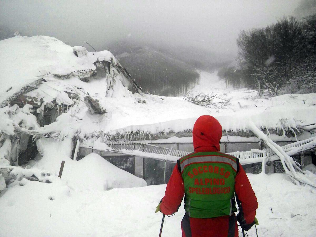 A rescuer on skis stands in front of the Hotel Rigopiano hit by an avalanche in Farindola, Italy, early Thursday, Jan. 19, 2017. 