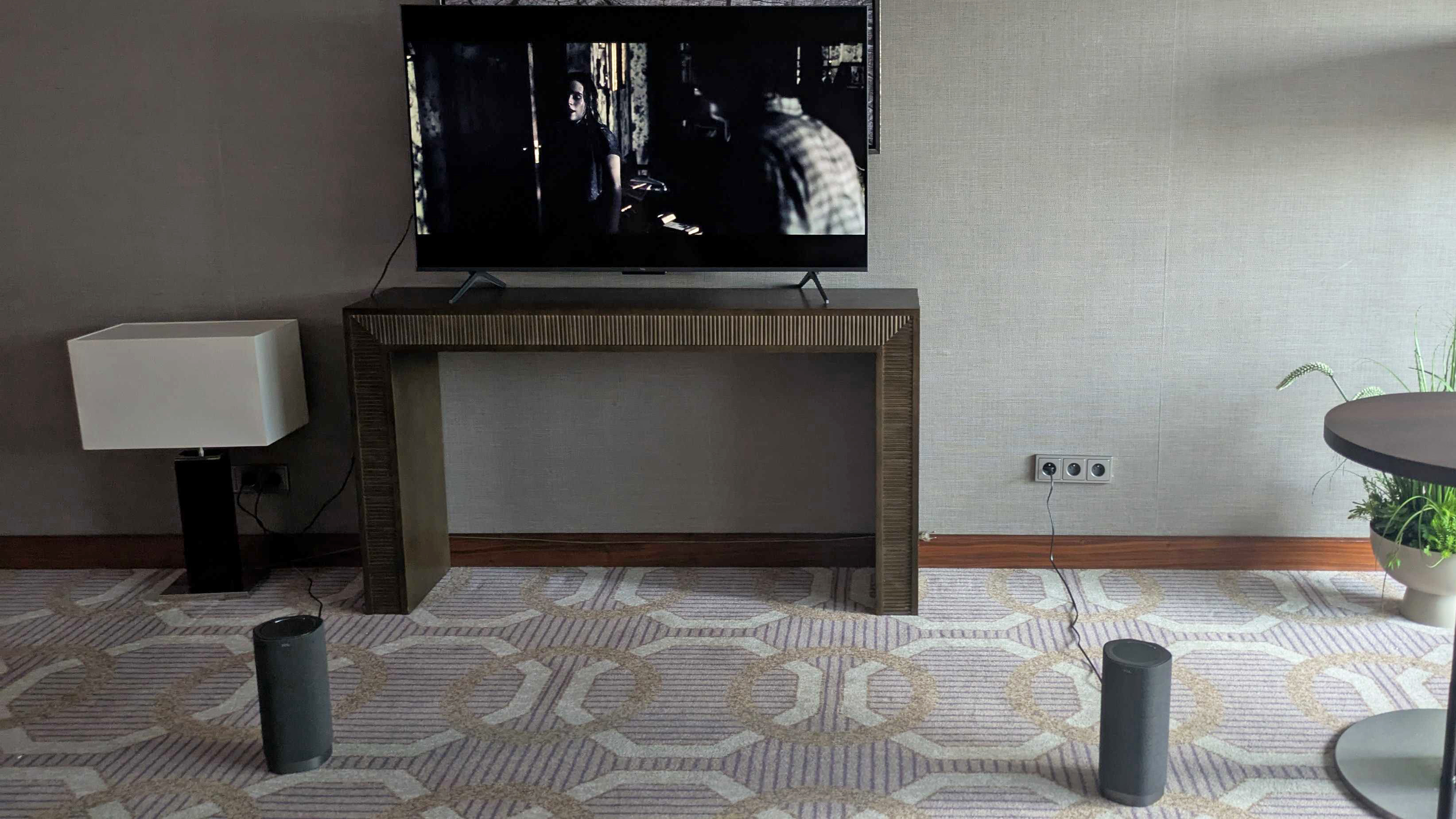 Two TXL Z100 speakers on the floor, in front of a TV