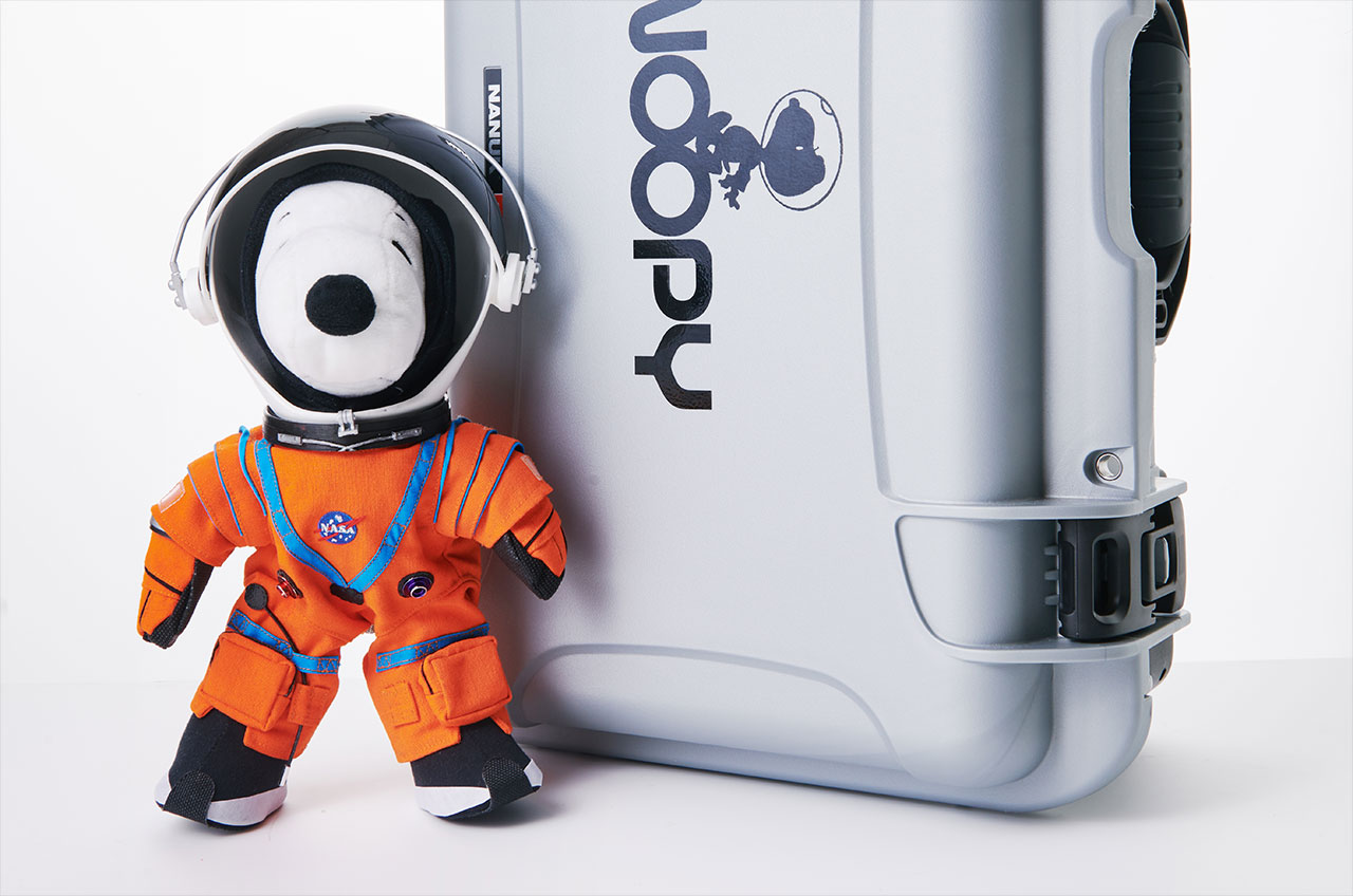 snoopy doll in a red spacesuit in front of a case