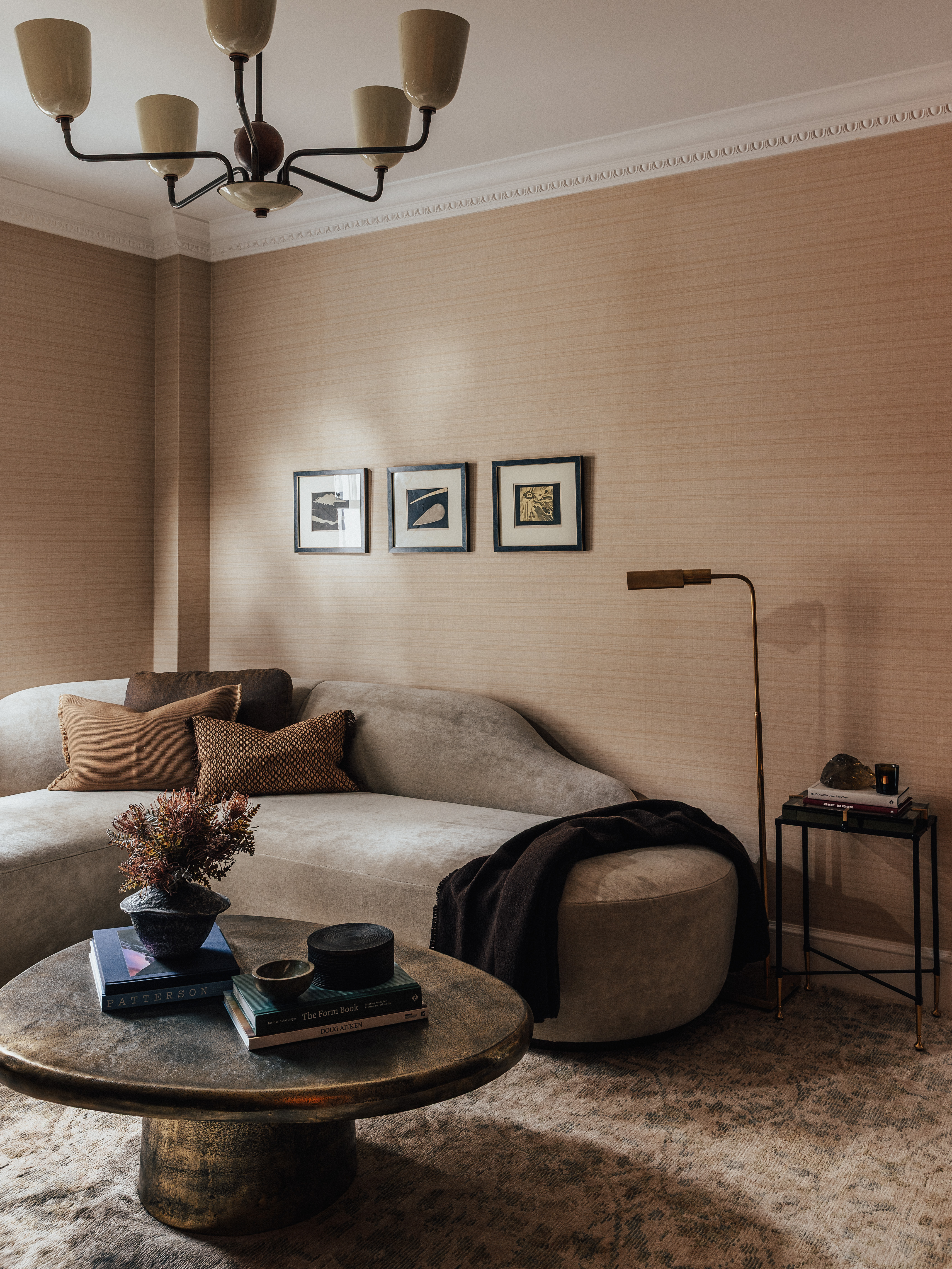 A contemporary living room with sculptural sofa, round coffee table and a trio of framed artworks on the wall