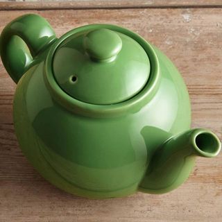 green teapot on wooden surface