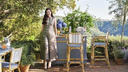 Hill House Home founder Nell Diamond smiling in front of an outdoor woven rattan bar set from her brand's new collaboration with Williams Sonoma 