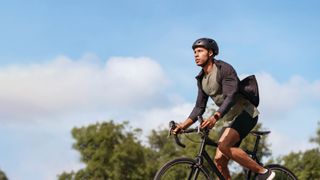 A man wears a Fitbit Sense while cycling