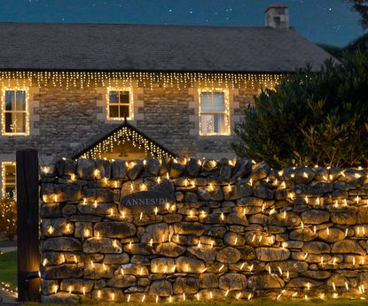 How to hang Christmas lights: exterior of house with lights on wall, porch and roofline