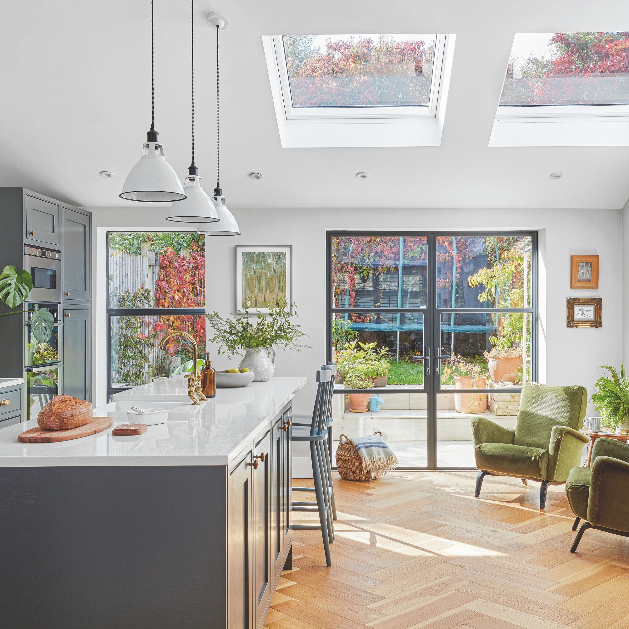 Open plan kitchen and living space with dark grey cabinets and a kitchen island, with accent chairs in the space beside it