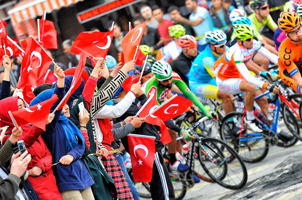 Fans wave Turkish flags as the peloton passes by
