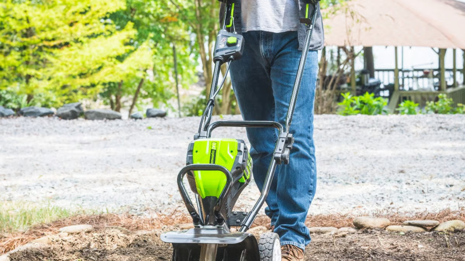 Man pushing GreenWorks tiller in garden bed