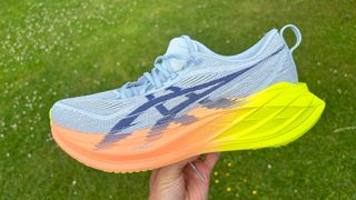 Asics Superblast 2 in a person's hand in front of grass
