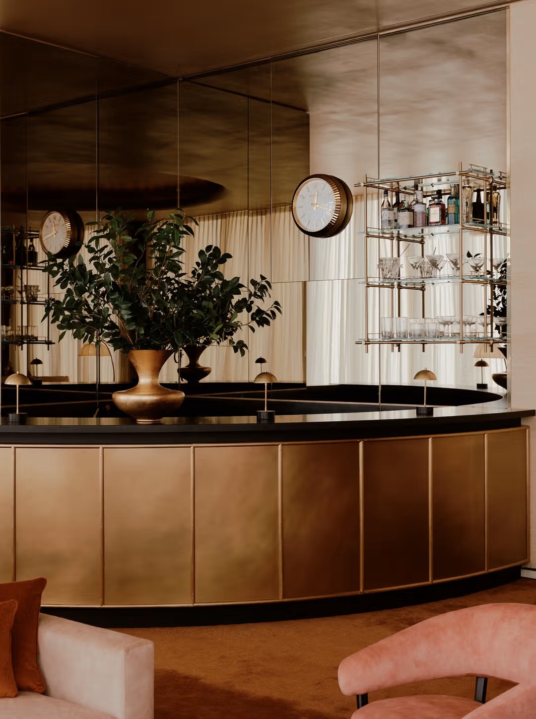 A sleek, brass, mirror, and velvet cocktail bar brings Art Deco extravaganza through revisited brass detailing, geometrical forms, and lavish serveware.