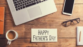Laptop, phone and Happy Father's Day note lay on table
