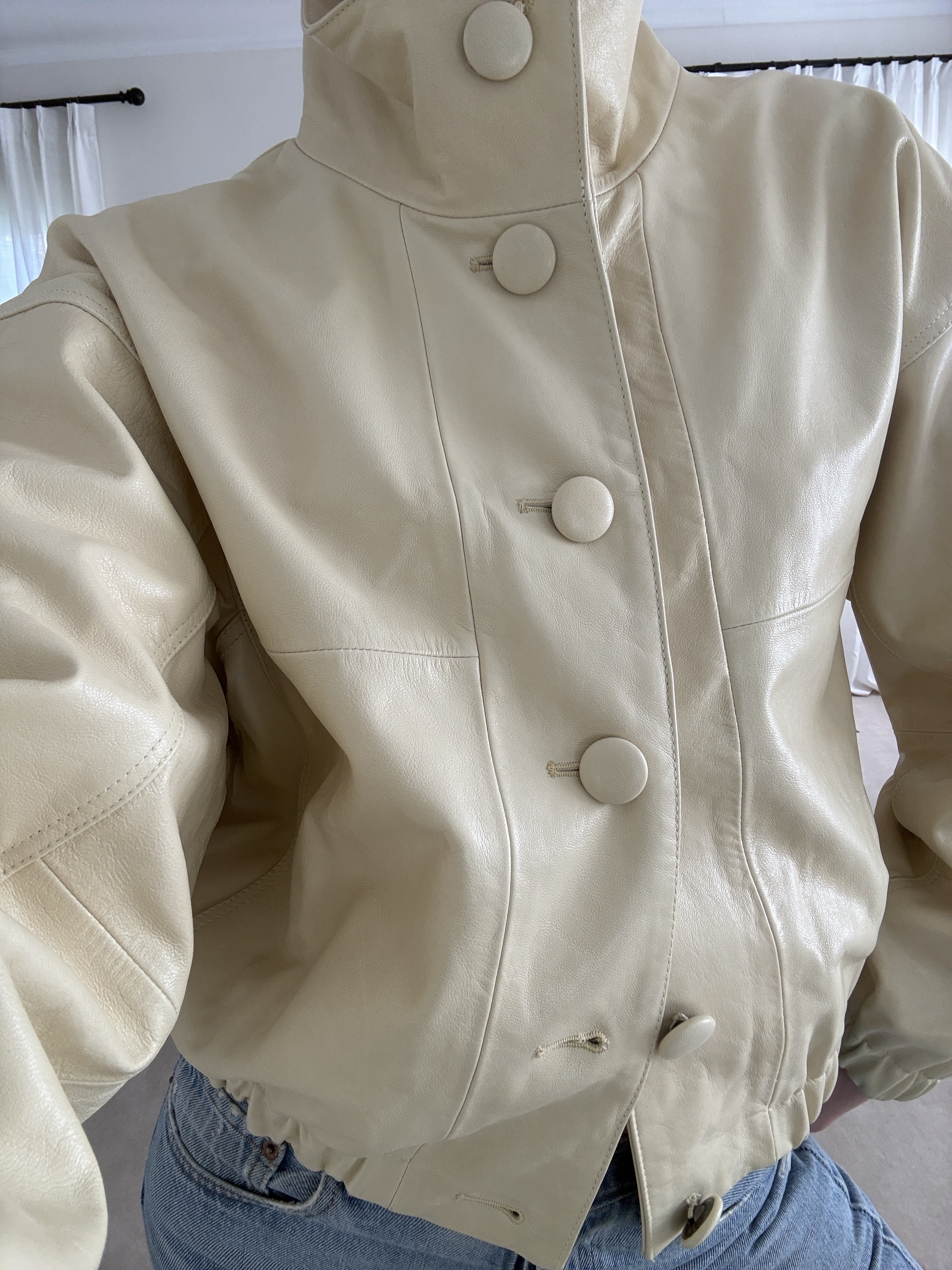 Christie Tyler wears a funnel-neck off-white bomber jacket