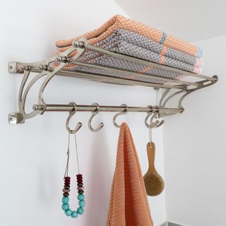 luggage shelf with towels on and hooks in bathroom
