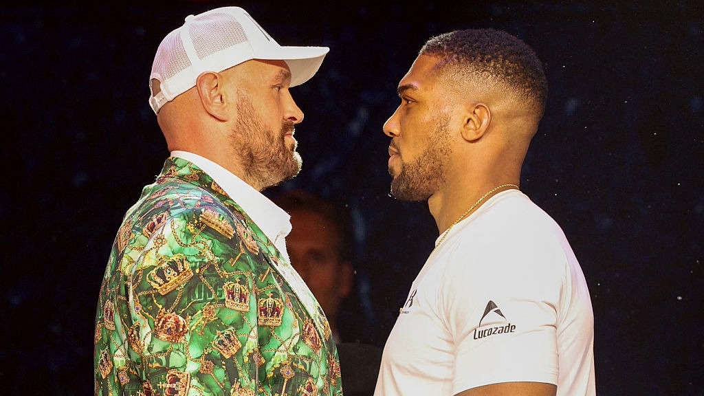Tyson Fury, wearing a baseball cap, and Anthony Joshua square off at a press conference ahead of their heavyweight tile fight.