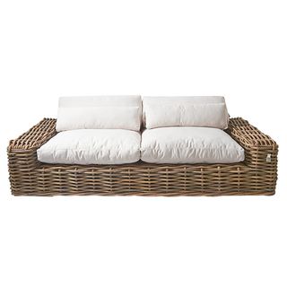 Rattan frame lounge sofa with plump white cushions