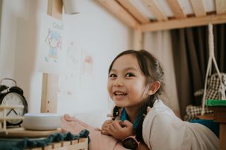 A little girl smiling next to a smart speaker