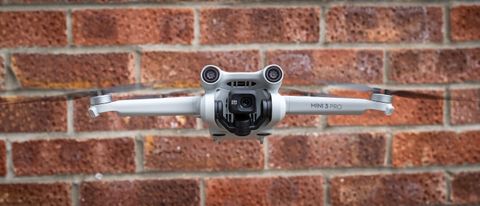 The DJI Mini 3 Pro flying on front of a brick wall