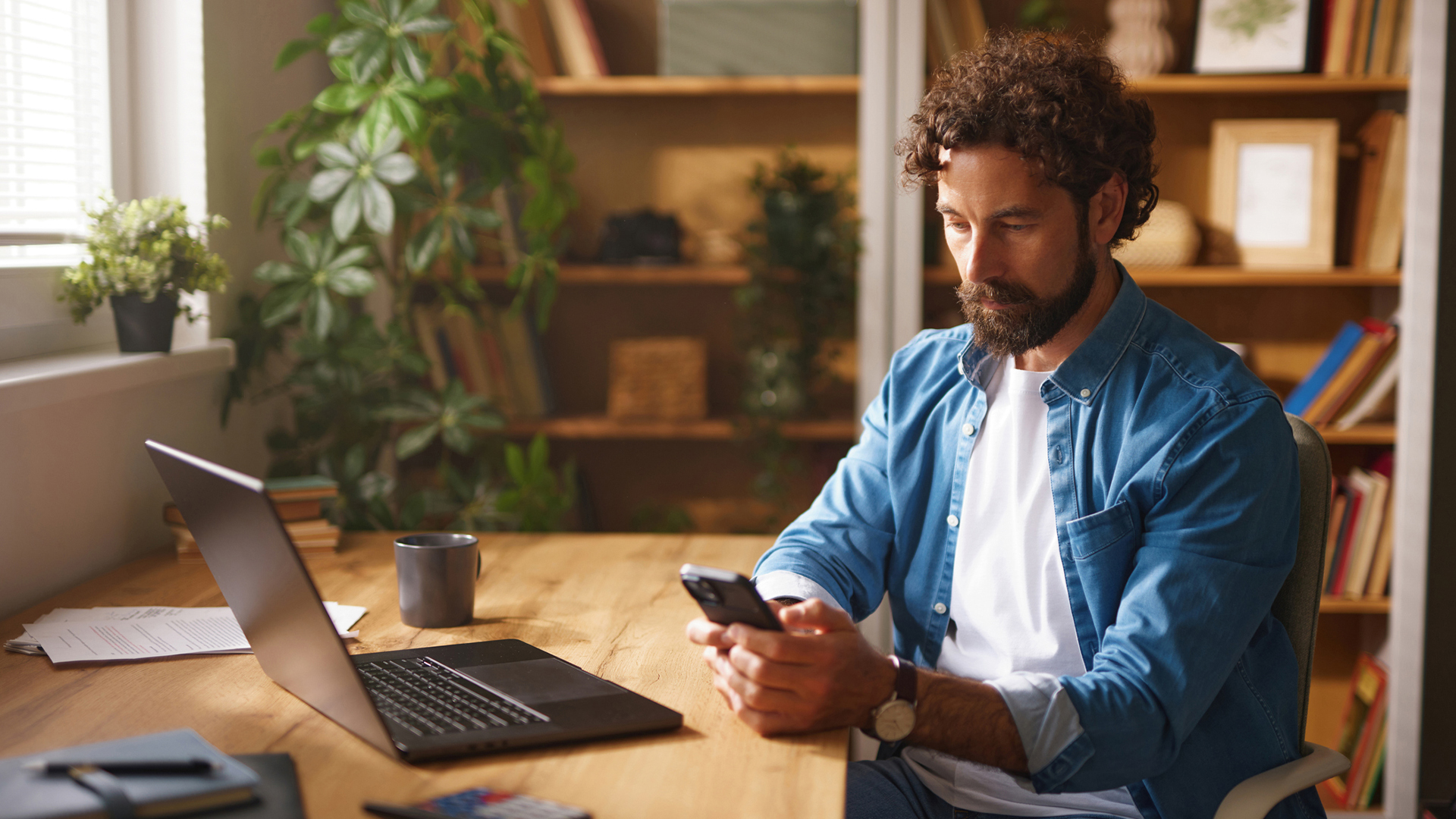 A man uses the phone as he sits by the desk