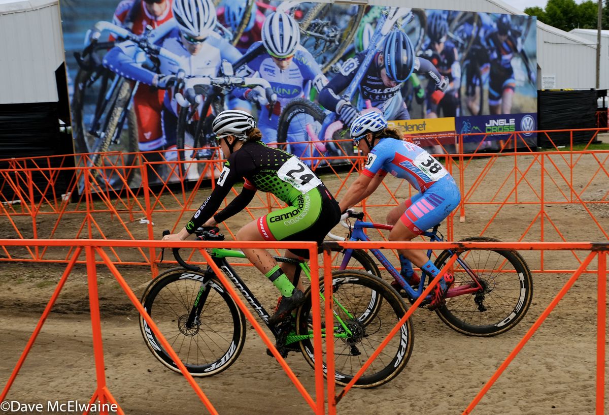 Ruby West (Cannondale) and Nicole Mertz (ISCorp) riding in front of the giant Jingle Cross mural