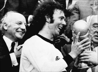 TOPSHOT - Germany's soccer star and team captain Franz Beckenbauer receives the World Soccer Cup won by his team after a 2-1 victory over Holland 07 July 1974 at Munich's Olympic stadium, as West Germany president Walter Scheel (L) applauds. Franz Beckenbauer, le capitaine de l'équipe d'Allemagne, reçoit la Coupe du Monde de Football 1974, à Munich le 07 juillet 1974. (Photo by AFP) (Photo by STF/AFP via Getty Images)