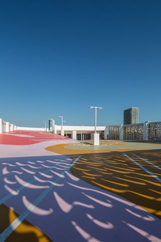 Roof playground, pastel colours, light casting shadows and patterns through the façades, clear blue sky