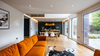 open plan living room and kitchen with orange sofa and wooden floor